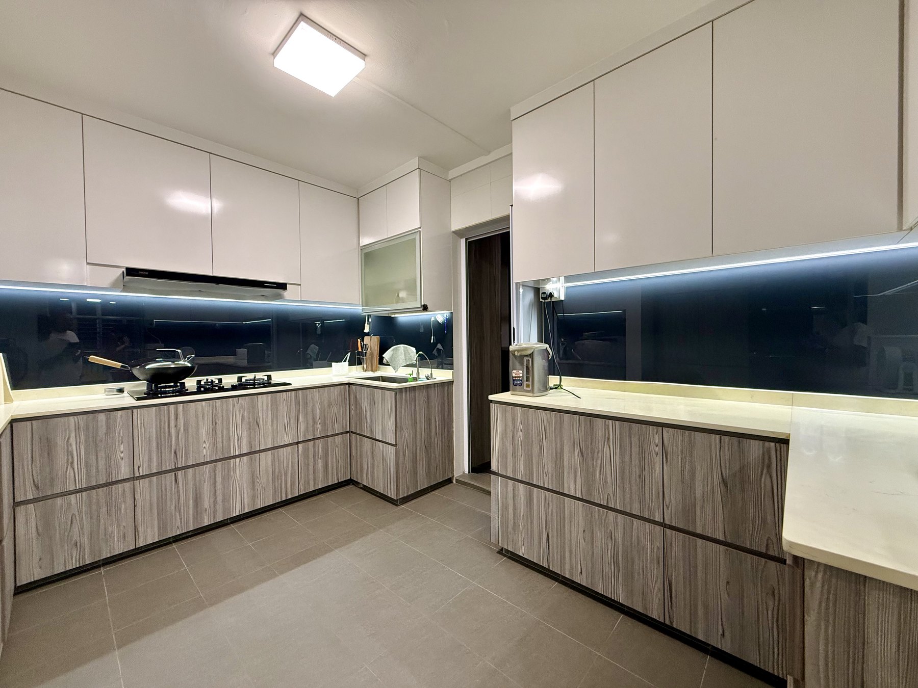 Renovated HDB kitchen with full-height white cabinetry and dark backsplash