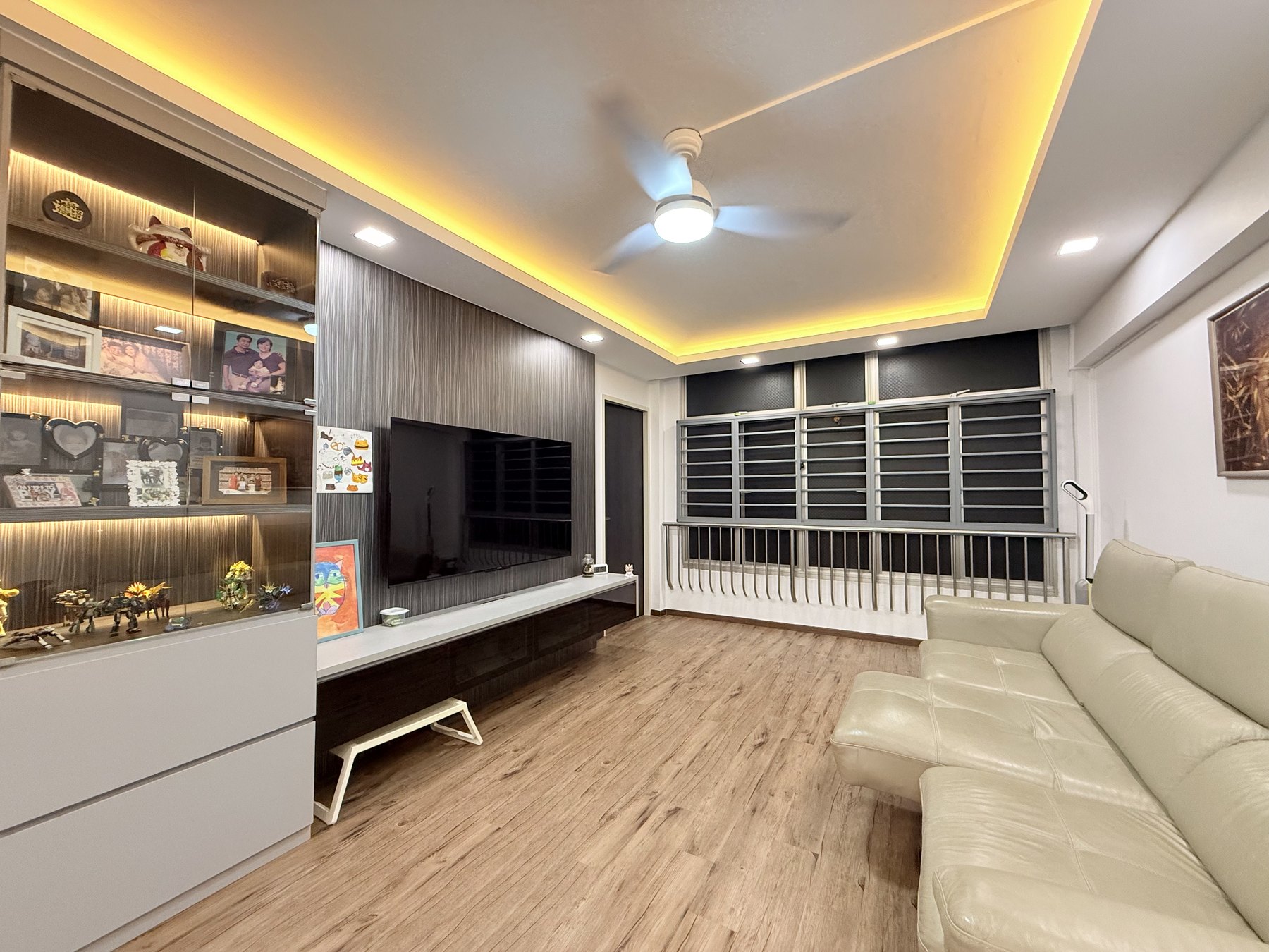 Renovated living room of the Toa Payoh 4-room HDB flat with built-in display cabinet and TV feature wall